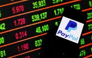 PayPal on phone in front of a stock market dashboard